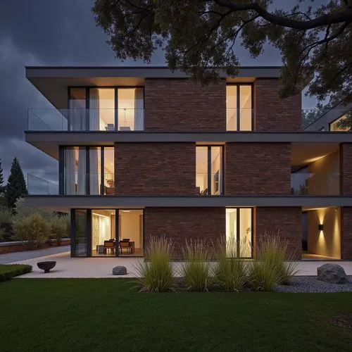 A photo-realistic rendering of a modern, two-story brick building with a contemporary design. the building is situated on a grassy area with a gravel path leading up to the entrance, and is lit up at 