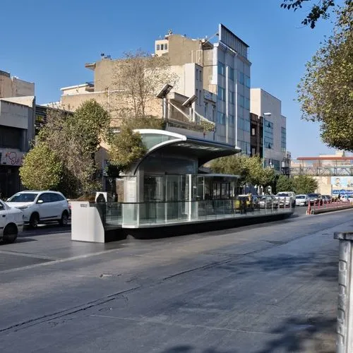 Design a modern station for a contemporary city using glass and grey composite materials. Include seating areas and advertising spaces. The roof should be curved.,a small bus stop next to some cars,di