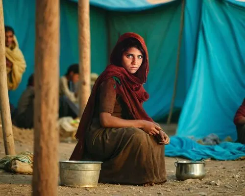 A wider scene around the young girl, set in a rustic, weathered refugee camp. Behind her, a backdrop of makeshift tents made of patched fabric and wooden poles tells a story of struggle and survival. 