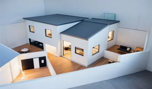 Una casa moderna de dos pisos con un diseño arquitectónico elegante y contemporáneo. La estructura cuenta con paredes de tonos blancos y grises, amplias ventanas de vidrio que permiten una iluminación