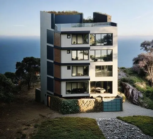 a three story building that overlooks the ocean,prefab,penthouses,peninsula,promontory,residential tower,peninsular