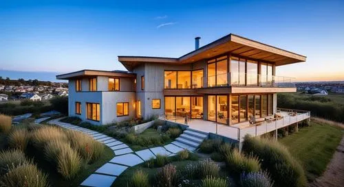 Aerial drone view looking down at a contemporary three-story hempcrete residence. Focus on the organic, porous texture of the hempcrete walls contrasted with natural wood window frames. The flat roof 