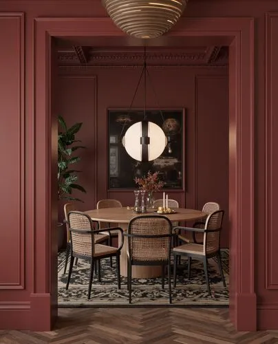 A sophisticated dining room with burgundy paneled walls and classic architectural details. A round wooden dining table is surrounded by cane-back chairs with black frames. A statement contemporary pen