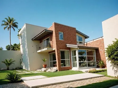 PHOTOGRAPH TAKEN WITH A KODAK CAMERA, WITH A 35MM LENS of a modern two-story house with a contemporary design, featuring a combination of brick and concrete. the house has large windows, sliding glass
