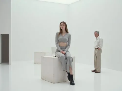 Photorealistic contemporary art gallery scene with a minimalist performance-art atmosphere.
A stylish young woman with a calm, confident presence sits elegantly on a modern lightweight metal chair pla