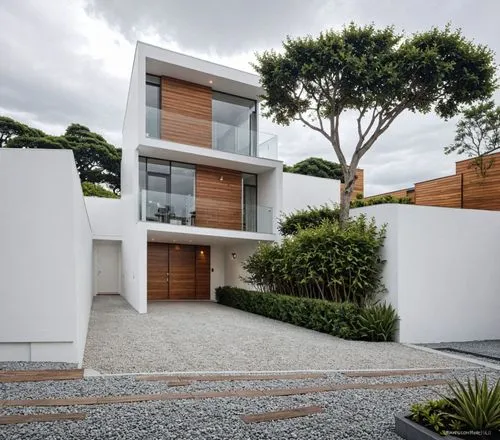 A photo-realistic rendering of a modern, minimalist two-story house with a contemporary design. the house is located in the middle of the image, with a large tree on the right side and a gravel drivew