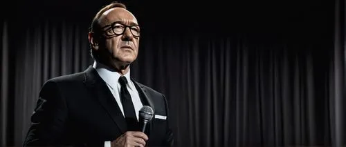 Mature man, Kevin Spacey style, formal wear, black suit, white shirt, black tie, holding a microphone, standing on a luxurious stage, elegant background, soft spotlight, serious facial expression, ico