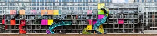 Create a colorful and dynamic gaming-themed building located at Sudkreuz Station in Berlin. The building should have a playful,  design with bright neon colors like blue, red, and orange, accented by 