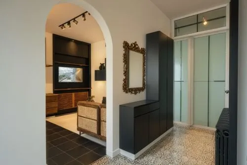 Living con pareti di colore neutro, specchio su porta a destra, ingresso con pavimento nero,there is an entrance with a flat screen tv and furniture,mudroom,walk-in closet,hallway space,hinged doors,e