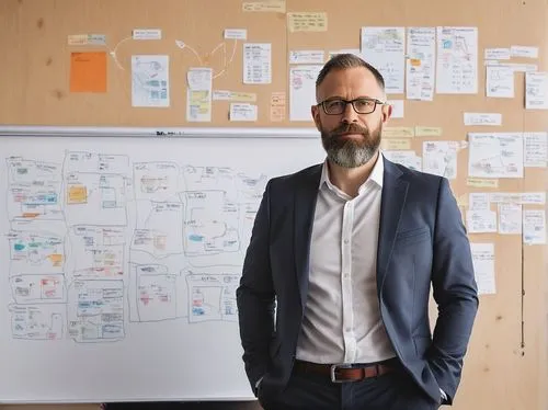 Software architect, mature man, (40yo), glasses, short hair, beard, formal wear, suit, tie, standing, in front of a whiteboard, markers, diagrams, UML, flowcharts, brainstorming, coffee cup, notebook,