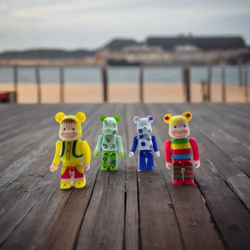 three colorful toys sitting on a wooden table near water,wooden figures,st ives pier,saltburn pier,wooden toys,nautical children,playmobil,Small Objects,Outdoor,Pier