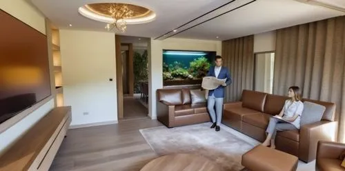 transparent glass of a fish tank over looking the dining area,a woman sits on a couch in front of a tv,modern room,smartsuite,guestrooms,modern decor,great room,contemporary decor