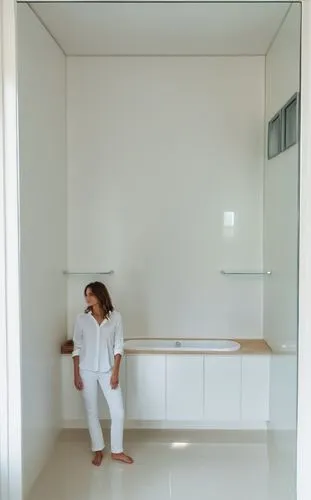 a nice bathroom, with a beautiful lady white shirt, black skinny jeans , bright morning light, white painted walls,a woman in a white shirt and jeans leaning against a window,modern minimalist bathroo