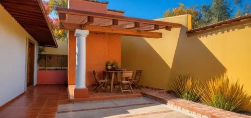 REMODELACION DE UNA CASA CON ESTILO MEXICANO, USO DE COLORES VIVOS, MADERA, PISOS DE BARRO, FLORES Y UN ESPEJO DE AGUA CON FUENTE EN UN MURO,a patio area with wooden umbrella shade and tables and chai