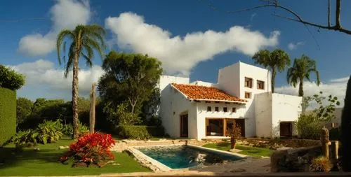 EL EXTERIOR DE UNA CASA CON ESTILO MEXCANO MODERNO, USO DE COLORES VIBRANTES, MATERIALES REFIONALES, TEJA, VIGAS DE MADERA, EN UN AMBIENTE EXUBERANTE, ESTANQUE DE AGUA AL FRENTE.,a house with grass, f