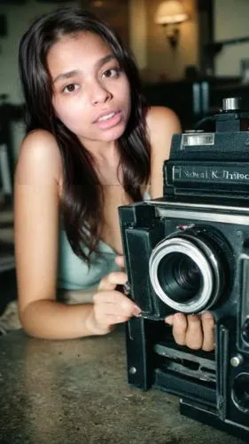 woman holding up an old camera on top of a table,digital camera,old camera,camera,vintage camera,analog camera,a girl with a camera,sony camera,vintage box camera,photo camera,twin lens reflex,halina 