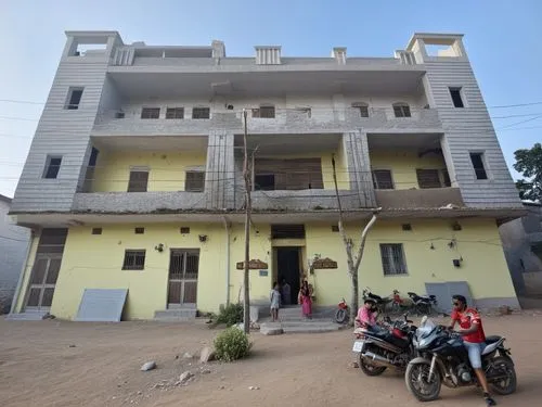 people are outside a yellow building with motorcycles parked in front of it,anganwadi,gandhipuram,kasturba,palanpur,palayamkottai,chakradharpur,Photography,General,Realistic