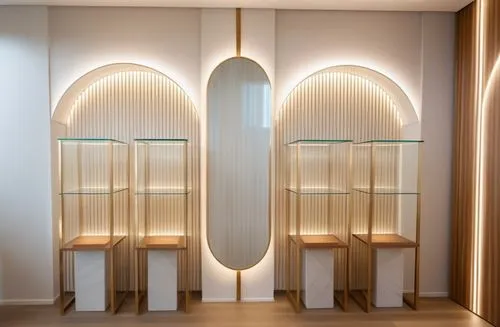 A jewelry display wall in glass vases, a light polymer wall covering and a fishbone wood floor and hidden lighting in each arc, a luxurious and bright style,a large mirror above some wooden tables,fos