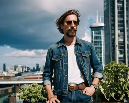 Male photographer, 30s, casual clothing, denim jeans, black t-shirt, silver watch, brown hair, messy style, beard, sunglasses, holding camera, standing, urban cityscape, modern skyscraper, glass and s