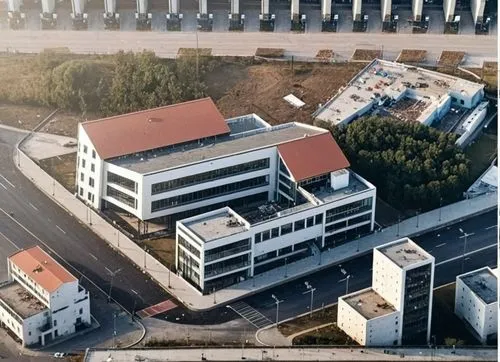 un edificio ubicado en una ciudad, su arquitectura esta basada en el constructivismo ruso.,an aerial view of a factory or medical office with the city below,iimura,technopark,company building,technion