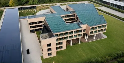 school building with a large elevated piloti space, situated at the front of the building is a playground. To the right of the building, there is a green area with a forest and a water feature.,archit