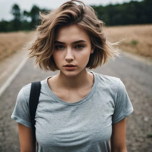 beautiful women, short brown hair, 20 years old, darker blonde hair, looking at the ground, baggy shirt, big chest, cute face, athletic body,a woman that is standing in the middle of the street,girl i