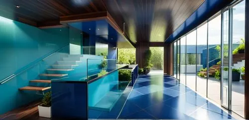 The ceiling and floor are all made up of dark-colored walnut trees, and the walls on the inside are covered in green plants. The central table is made of cobalt blue plastic, the walls on the stairs a