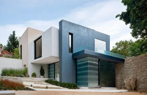 DISEÑO DE UNA CASA RESIDENCIAL EN ESQUINA CON UN VENTANAL EN ESQUINA , CON CANCELES DE ALUMINIO Y CRISTAL, EXCELENTE REPRESENTACIÓN, PROPORCION, VEGETACION EXUBERANTE,an all white house with a black b