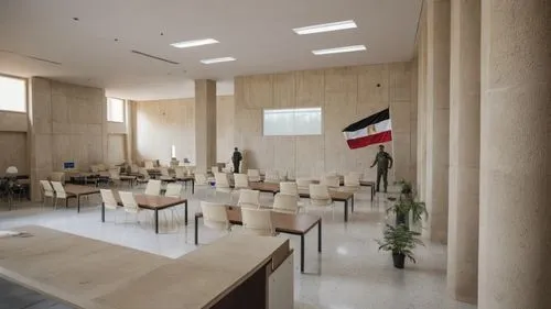 A visiting hall where parents visit their children. The hall contains sitting rooms, desks, the Egyptian flag, surveillance cameras, and police officers to secure the place. There are concrete columns