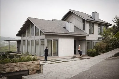 perspective, mid shot, residence, holiday home, house on a hill terrain, misty day, contemporary style, Mid century, White brick house,  Grey tile roof, fireplace chimney, landscaping, road pavement, 