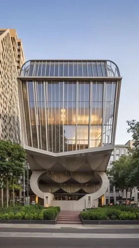 A magnificent building towering above the bustling streets of an urban neighborhood. This architectural marvel features sleek, modern lines and a facade adorned with expansive glass panels that reflec