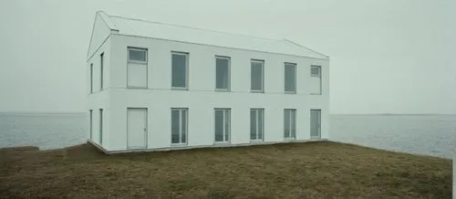 a white building with a pointy roof on a grassy hill,cubic house,cube house,hejduk,danish house,mirror house,malaparte,Photography,Documentary Photography,Documentary Photography 04