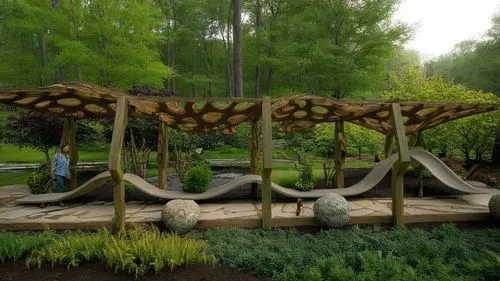 a wooden play area with stone balls, a green yard, and a wooden structure with arches,ecopark,crocodile park,nature garden,camarasaurus,sauropods,sauropod,Photography,Documentary Photography,Documenta