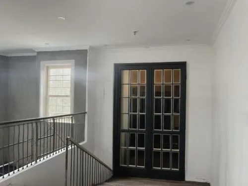 glass window pane,a staircase leading to a second story in a house,entryway,steel door,hinged doors,hallway space,foyer,metallic door