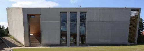 edificio audiovisual de 3 metros de altura de una facultad de arquitectura, en un paisaje rural estilo brutalista y moderno, con materiales como placas de hormigon armado y acero en las ventanas  ,chr