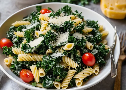 White bowl filled with Kale Caesar Pasta Salad garnished with fresh Parmesan cheese,rapini,creamed spinach,gremolata,lacinato kale,fusilli,rotini,pasta salad,cavatappi,mustard greens,sea salad,tagliat