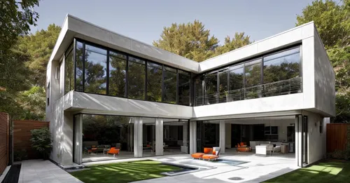 a modern modern house with polished floors and flowing windows sits at the end of a quiet garden. The windows are painted a soft orange, and the doors are painted a deep red. The primary exterior colo