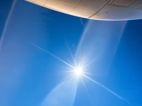 the airplane wing looks very clear with the sun shining down,thermosphere,troposphere,heliosphere,stratospheric,ionosphere,geoengineering