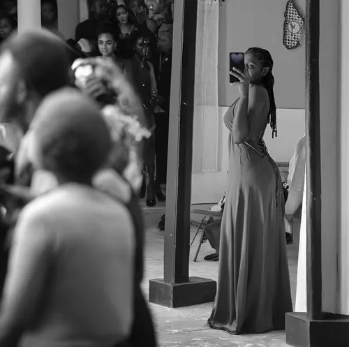 Beautyfull young african woman. Black and white. Watched by many spectators in a Fashion public show,girl in a long dress from the back,a girl with a camera,paparazzi,girl in a long dress,woman holdin