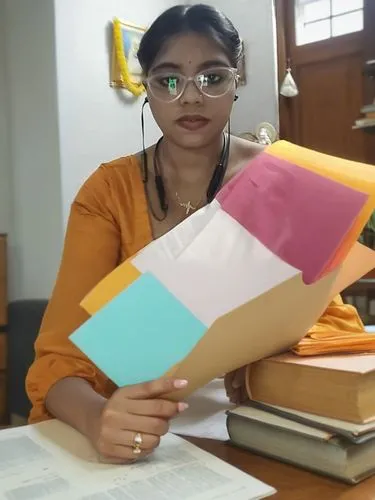 a lady that is sitting at a desk with some papers,paper umbrella,origami paper plane,akhila,page dividers,envelopes,folded paper