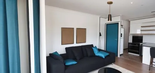  beautiful living room with brilliant white walls, bright and beautiful day outside, city apartment with a balcony with grass, beautiful black pendant light, teal blue curtains, white sheers, comfy bl