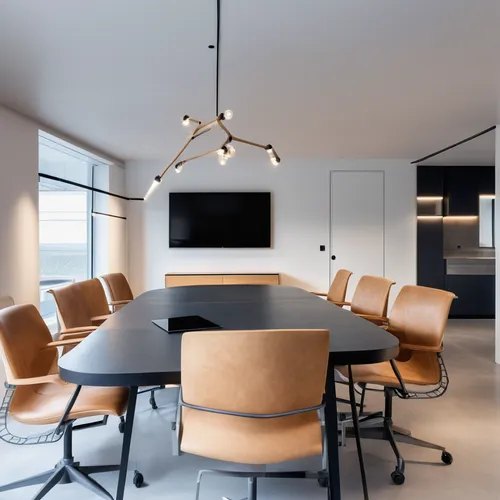 meeting room, white stucco walls, microcement flooring. A table with a black lacquered top and dark wooden legs in the center, eight chairs with wheels with metal structure and seat and back in black 