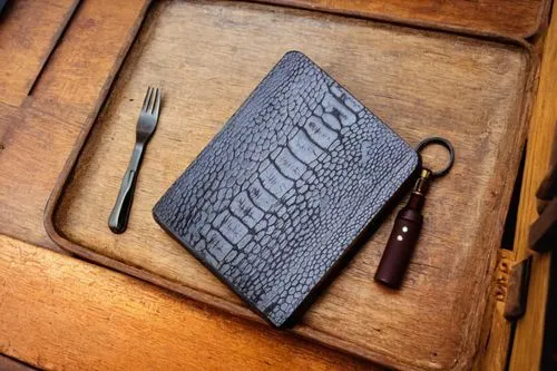 an opened notebook and knife on top of a wooden table,embossing,leather goods,letterpress,leatherwork,bookbinders,photoengraving