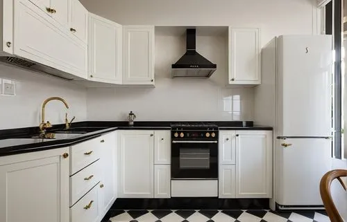 a white kitchen with black countertops and gold hardware,kitchen design,dark cabinets,tile kitchen,dark cabinetry,vintage kitchen,kitchen interior,kitchens,modern kitchen interior,gaggenau,kitchenette