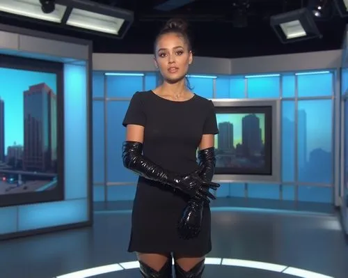 A young female news anchor is live on air in a modern TV studio, presenting the evening news. She’s dressed in a simple, short-sleeved dress that is modest and professional. However, her outfit is une