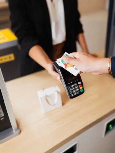 a woman standing behind a cash register at an atm,payment terminal,electronic payments,cashiering,electronic payment,card payment,payments