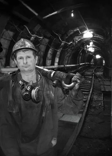 a man wearing a hard hat holds up a hammer,coalminer,coalmining,underminer,miner,coalminers,coal mining