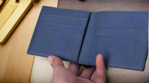 a hand holding a blue book near a piece of wood,scrape book,reichstul,kraft notebook with elastic band,prayer book,bookbinding,moleskine