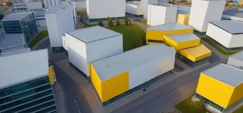 the building in yellow is a hospital next to a grey office campus and a school beige in colour and across the road is an art gallery  the buildings in qhite are resdential and comnmercial offices add 