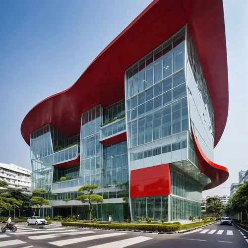 ISLAMIC CANCER  HOSPITAL, TWO STOREYS, SURABAYA, STREET JUNCTION, RED CRESCENT LOGO, PERFORATED BLACK METALS BUILDING COVER, LARGE PARKING AREA AT FRONT, LARGE STEEL COLLONADE , GOLDEN LINING, EXPOSED